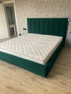 Green upholstered bed and panelled headboard