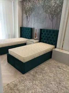 Matching green single beds and tufted headboards